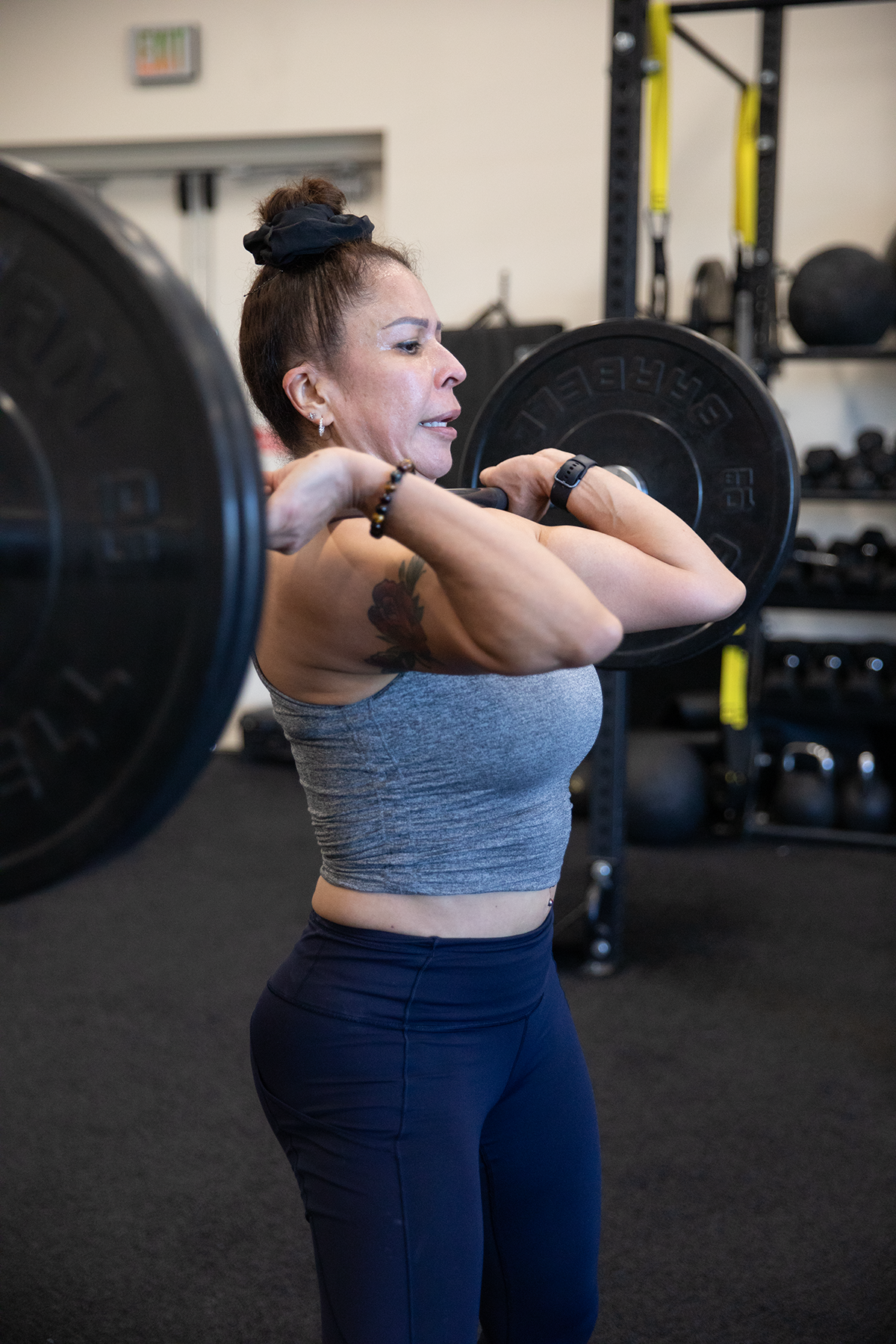 A strong woman lifts a weight onto her shoulders.