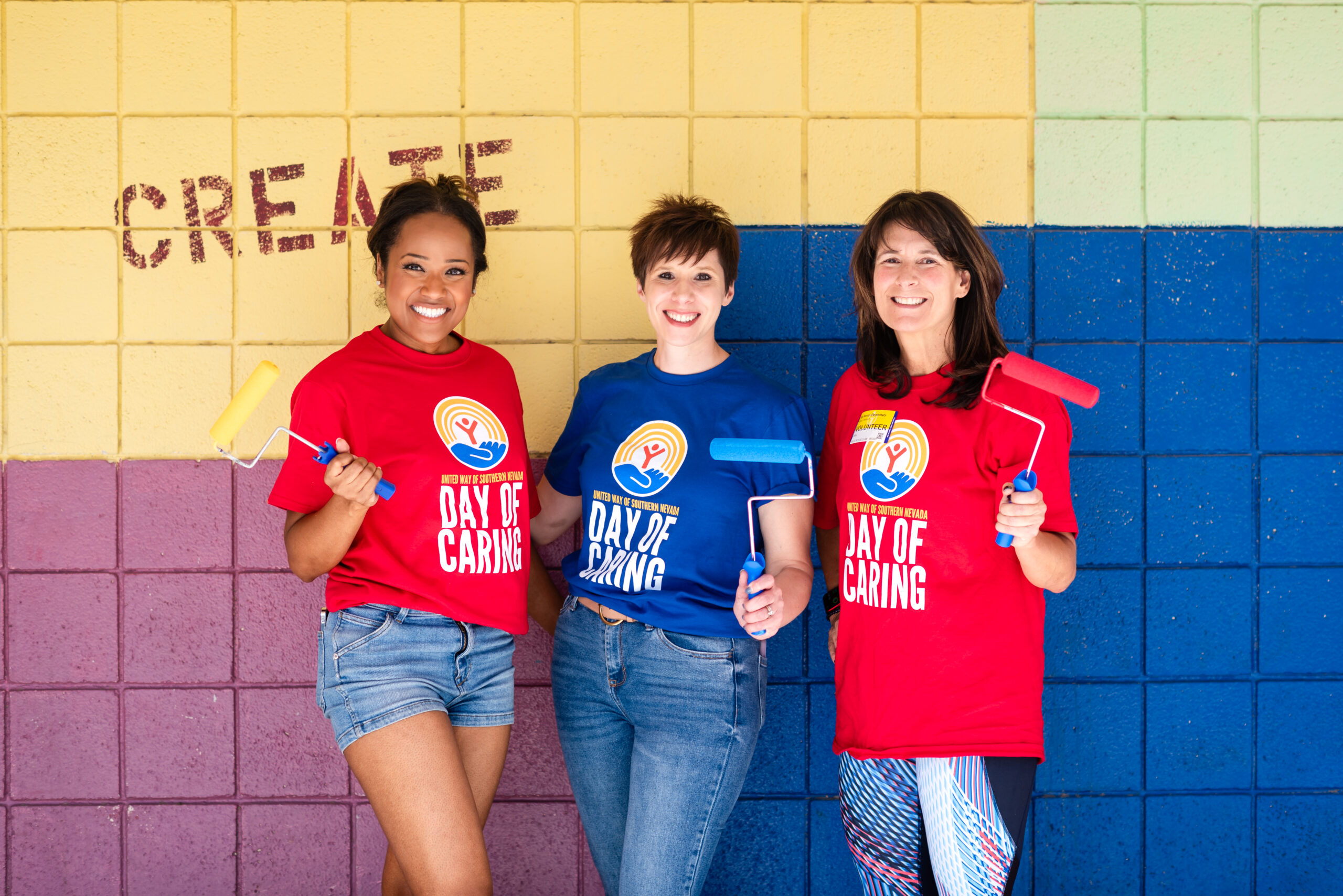 Three happy volunteers hold up painting supplies at the United Way Day of Caring 2024.